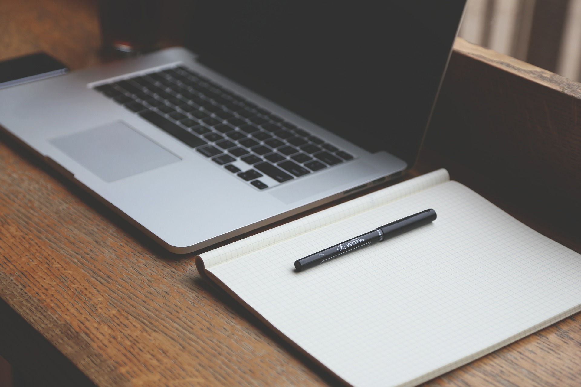 Photograph of a laptop computer next to a notebook.