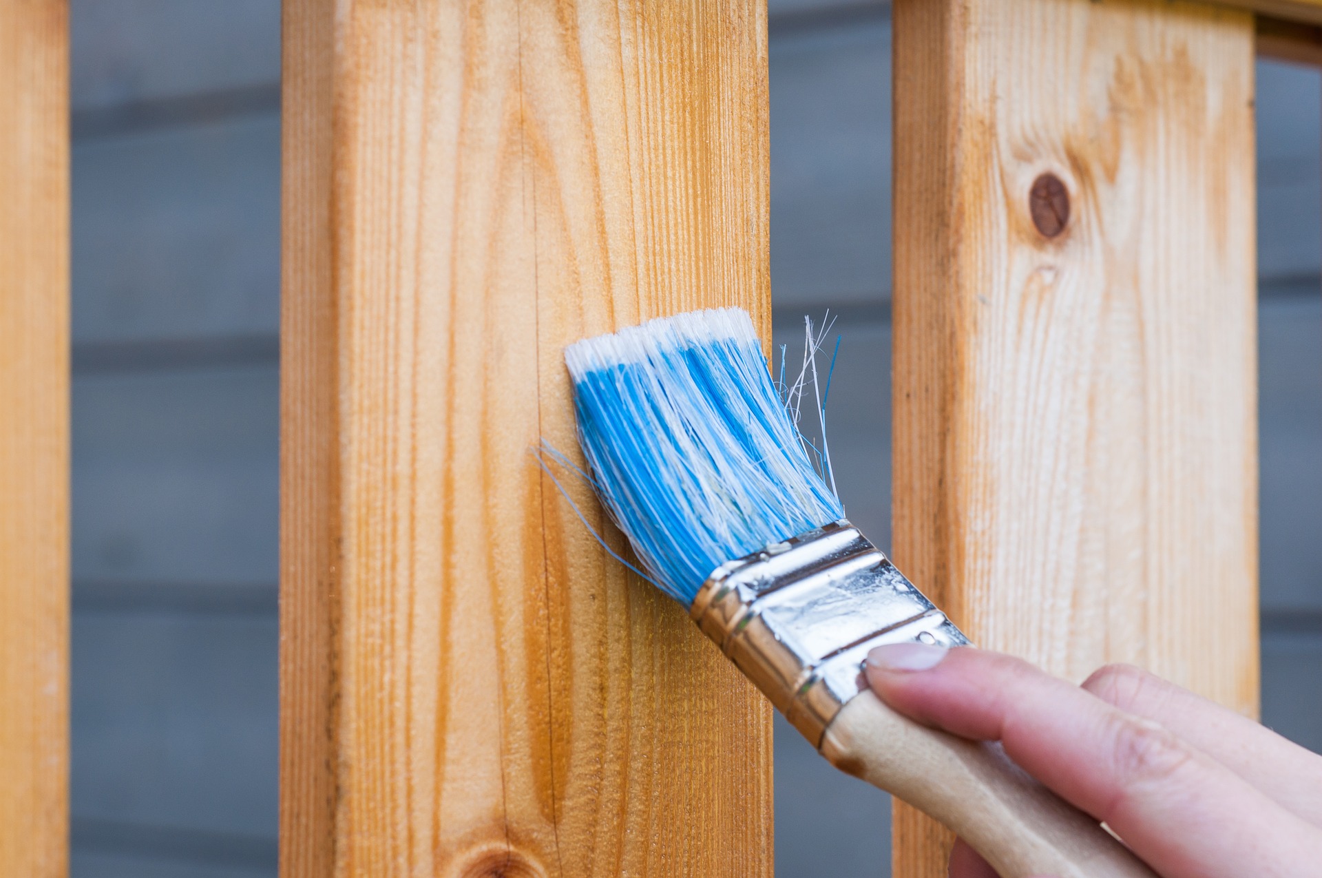 Photograph of someone painting a fence board.